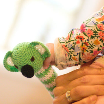 Baby holding fair trade crochet koala rattle